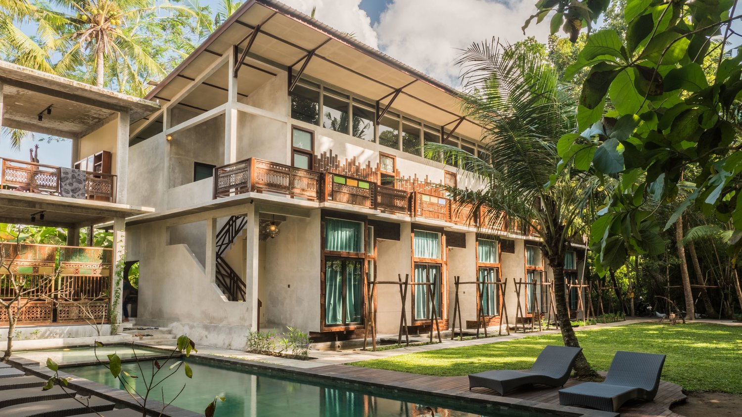 A tropical retreat villa with a pool, palm trees, and morning light — Pangea retreat center